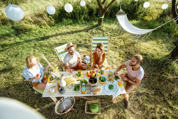 Dostlar bahçede şenlikli bir öğle yemeği yerken — Stok fotoğraf