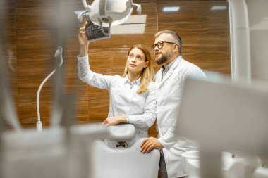 Ofisteki röntgen görüntülerini inceleyen dişçiler