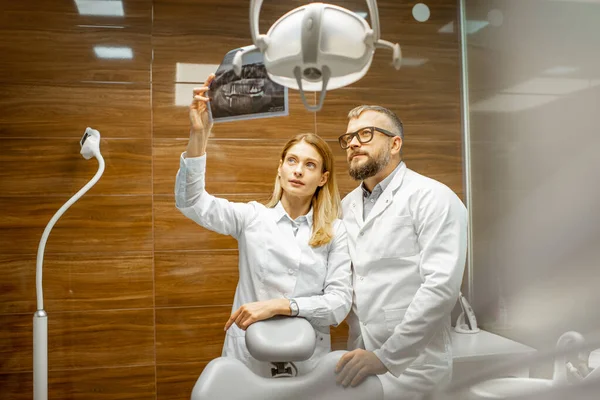 Tandartsen onderzoeken röntgenfoto op kantoor — Stockfoto