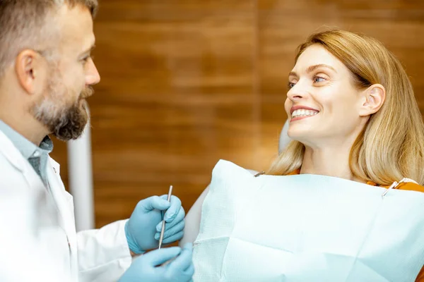 Дорослий пацієнт з стоматологом посміхається під час медичної консультації — стокове фото