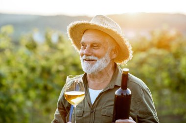 Şarap üreticisi üzüm bağında şarap tadıyor.