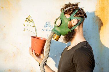 Gaz maskeli ve saksısı olan adam.