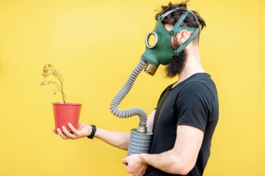 Gaz maskeli ve saksısı olan adam.
