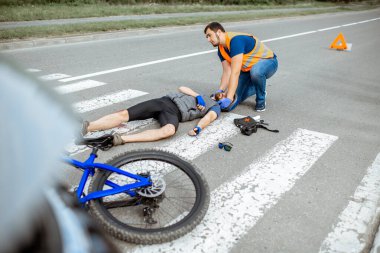 Yaralı bisikletçi ve ilk yardım sağlayan adamla trafik kazası.