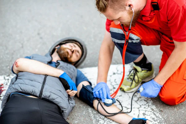 Elsősegélyt nyújtó orvos a sérült számára az úton — Stock Fotó