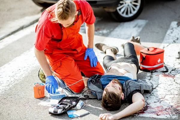 Médico aplicando atención de emergencia después del accidente de tráfico —  Fotos de Stock