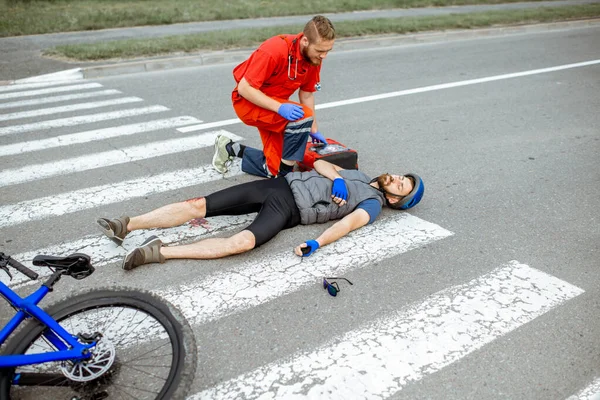 Medic applying first aid to the injured man on the road