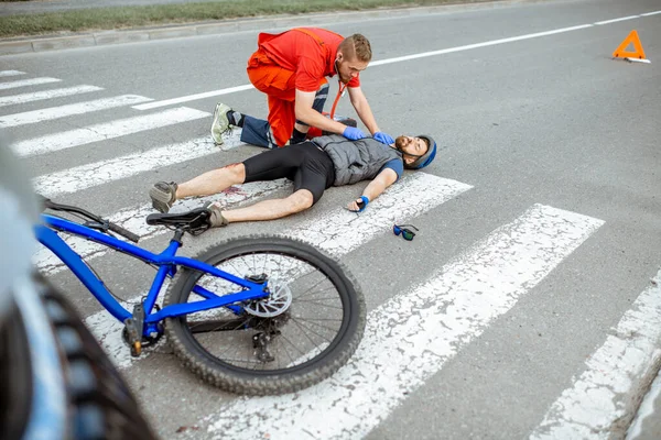 Médico aplicando primeiros socorros ao homem ferido na estrada — Fotografia de Stock