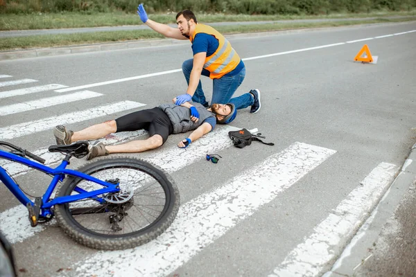 부상을 입은 자전거 선수와 응급 치료를 해 주는 사람 의사고 — 스톡 사진