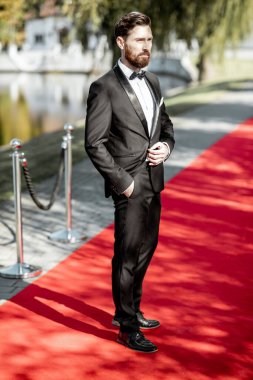 Kırmızı halıdaki smokinli adam.