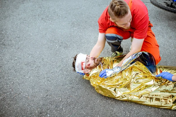 Kazadan sonra kurbanın üstünü termal battaniyeyle örten doktor. — Stok fotoğraf