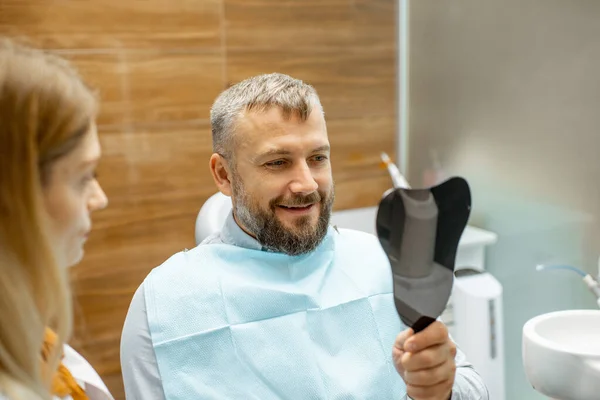Пациент с зубным зеркалом в стоматологическом кабинете — стоковое фото