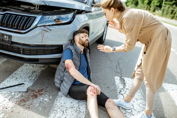 Kobieta kierowca z rannym mężczyzną na drodze — Zdjęcie stockowe