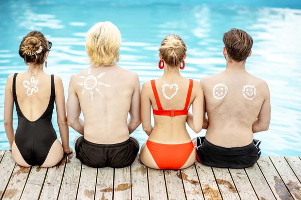 Друзі з сонячним кремом на басейні на відкритому повітрі — стокове фото