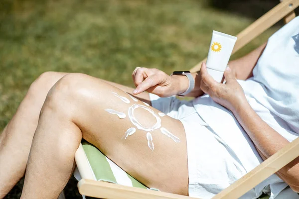 Senior woman with sunscreen lotion — Stock Photo, Image