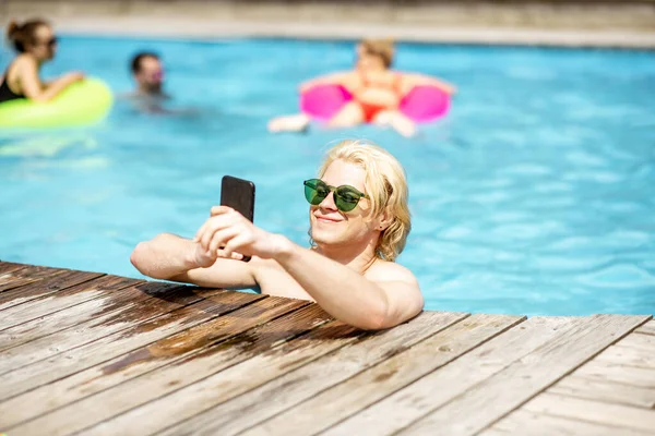 Hombre con teléfono en la piscina —  Fotos de Stock