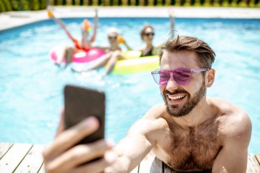 Yüzme havuzunda telefonu olan adam.