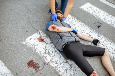 Yaralı bisikletçi ve ilk yardım sağlayan adamla trafik kazası.