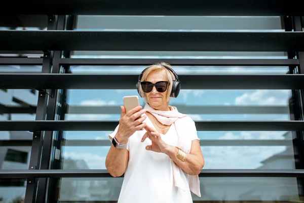 Elegante donna anziana ascoltando la musica all'aperto — Foto Stock