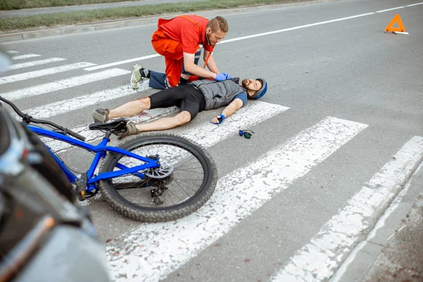 Médico aplicando primeros auxilios al herido en la carretera —  Fotos de Stock