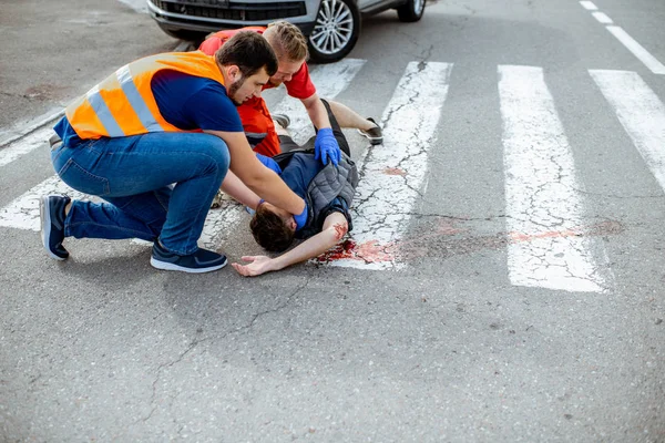 Aplicando primeiros socorros para a pessoa sangrando na estrada — Fotografia de Stock