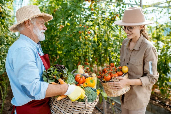 Дедушка с молодой женщиной и урожай овощей — стоковое фото