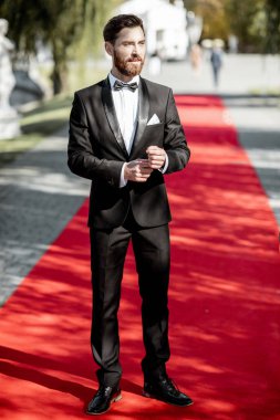 Kırmızı halıdaki smokinli adam.