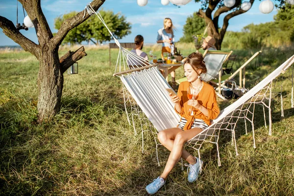 女性とともに携帯電話オンザハンモック屋外 — ストック写真