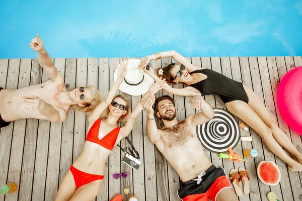 Friends sunbathing on the swimming pool — Stock Photo, Image