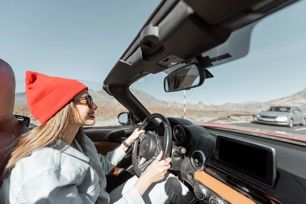 Woman traveling by cabriolet car on the desert road — Stock Photo, Image