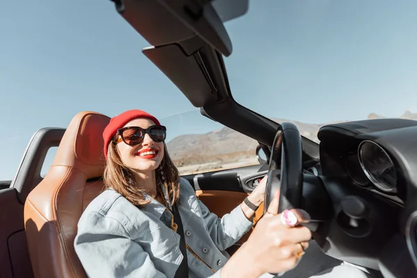 Woman traveling by cabriolet car on the desert road — Stock Photo, Image