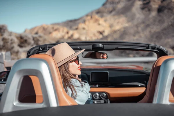 Woman traveling by cabriolet car on the desert road — Stock Photo, Image