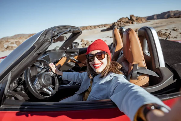 Woman traveling by cabriolet car on the desert velley — Stock fotografie
