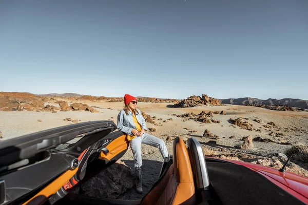 Woman traveling by cabriolet car on the desert valley — Stockfoto