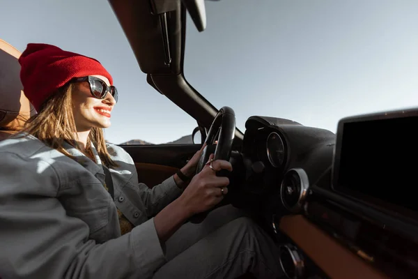 Woman traveling by cabriolet car on the desert road