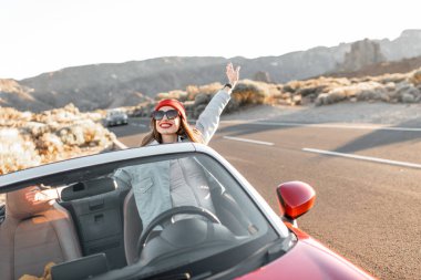 Cabriolet arabasıyla seyahat eden mutlu kadın.
