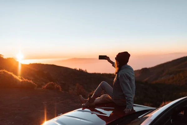 Woman enjoying beautiful sunset while traveling in the mountains by car — Stock Fotó