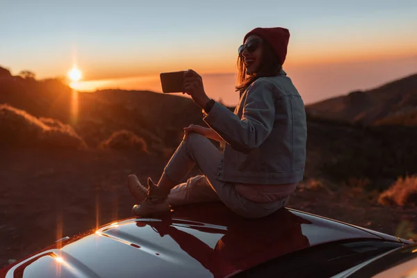 Женщина наслаждается прекрасным закатом, путешествуя по горам на машине — стоковое фото