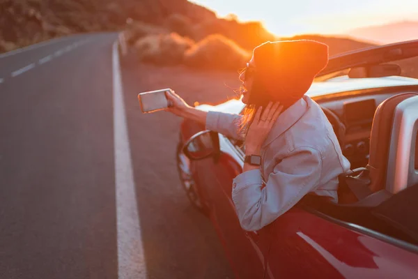 Mujer viajando en coche en una hermosa carretera durante una puesta de sol — Foto de Stock