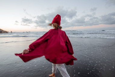 Lifestyle portrait of a carefree woman on the beach at dusk