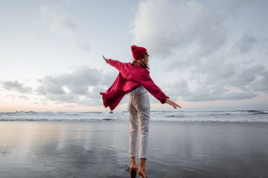 Lifestyle portrait of a carefree woman on the beach at dusk