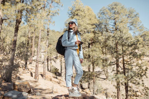 Woman hiking in the forest highly in the mountains on a volcanic rocks — Stock Photo, Image