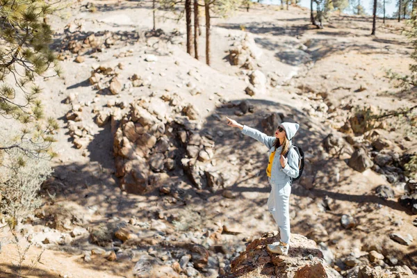 Woman hiking in the forest highly in the mountains on a volcanic rocks — Stockfoto