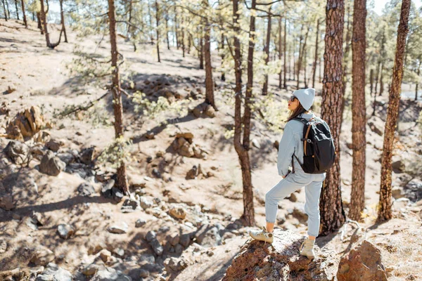 Femme randonnée dans la forêt très en montagne sur un rocher volcanique — Photo