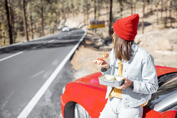 Woman eating during a roadtrip in the mountains — Stockfoto