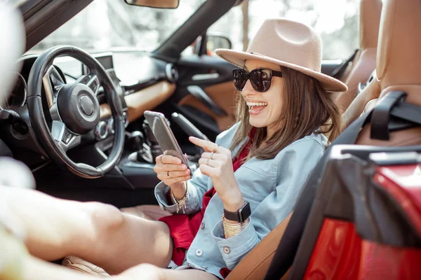 Woman tarveling by car and using phone — Stockfoto