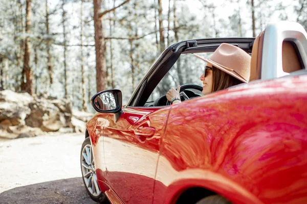 Woman driving a cabriolet while traveling in the forest — 图库照片