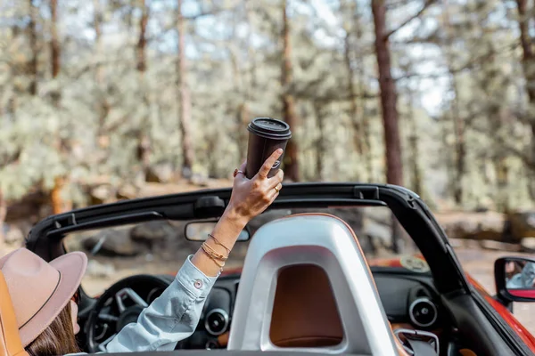 Mulher dirigindo um cabriolet enquanto viaja na floresta — Fotografia de Stock