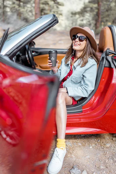 Retrato de uma mulher em cabriolet vermelho na beira da estrada durante uma viagem — Fotografia de Stock