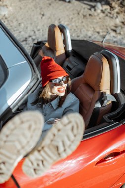 Çöl vadisinde üstü açık arabayla seyahat eden bir kadın.